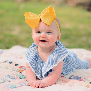 A baby laying on a mat outdoors in tummy time
